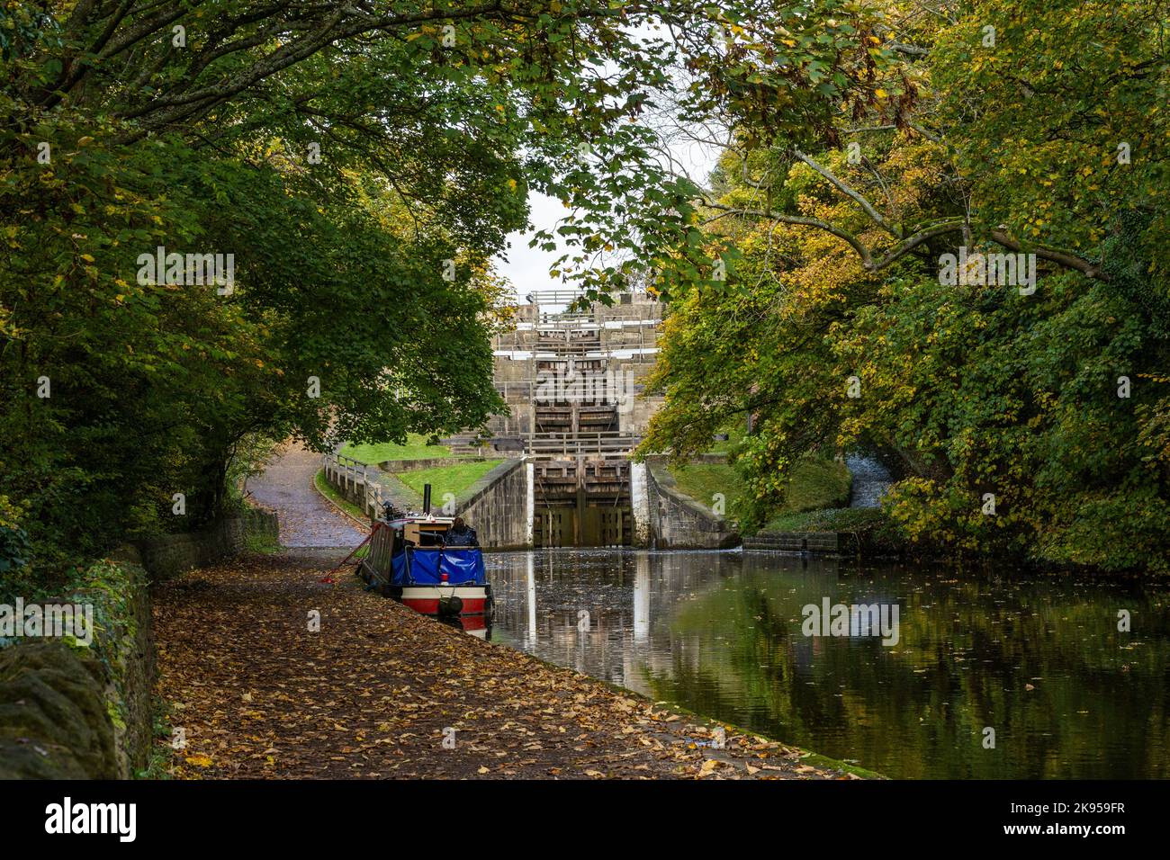 A barge (narrowboat) is moored up at the side of the Leeds Liverpool canal below Five Rise Locks (Staircase lock)  in Bingley, West Yorkshire. Stock Photo