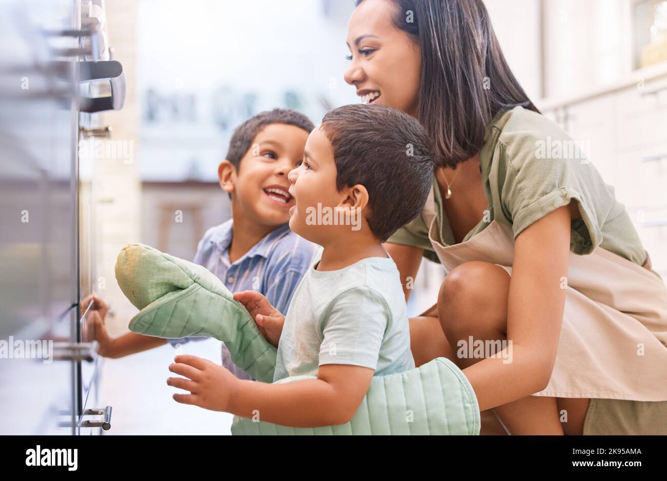 Family kids bonding, baking and mother happy at a kitchen oven spending quality time. Mama and children smile together with love and care learning to Stock Photo