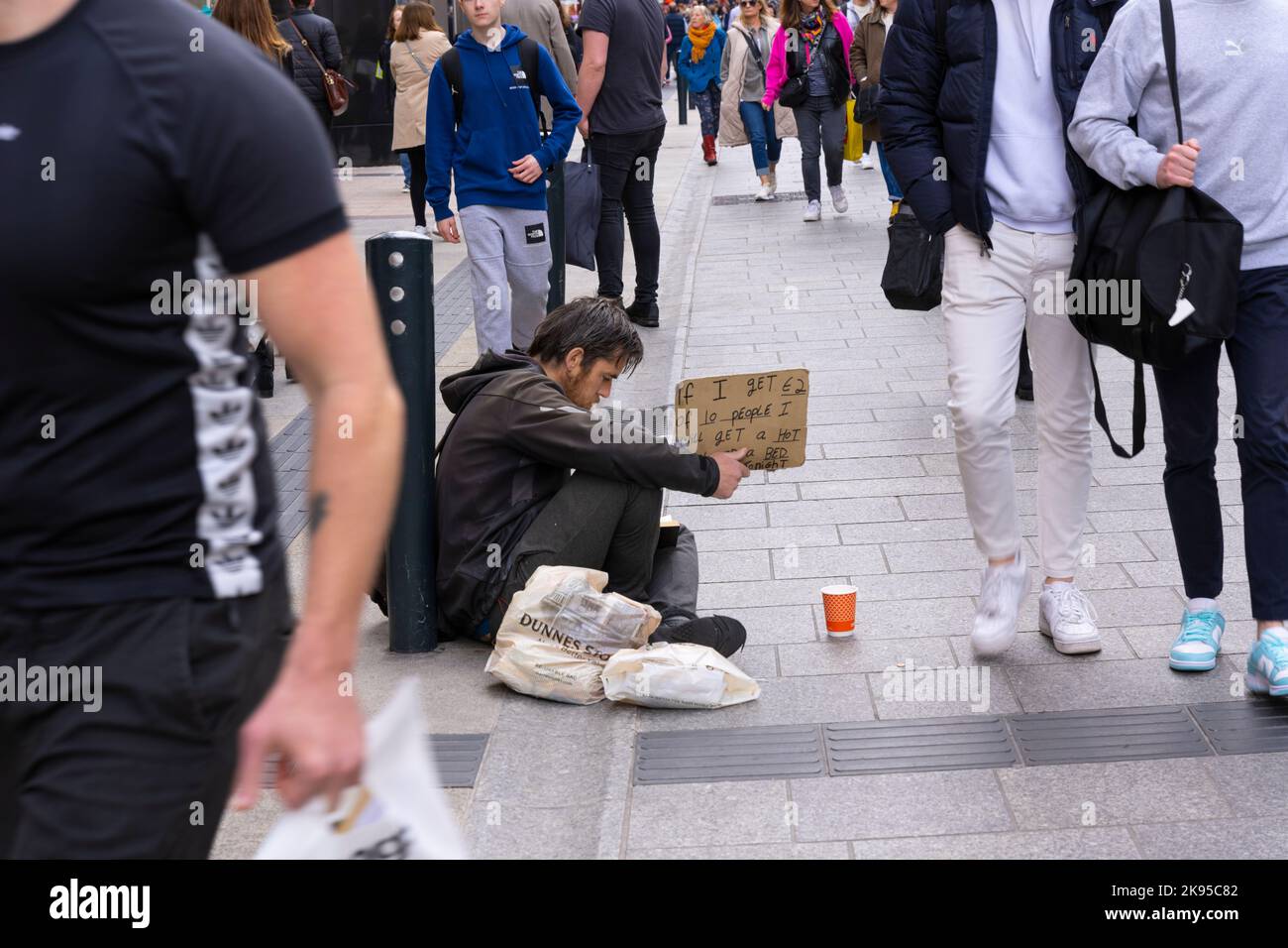 Ireland Dublin Grafton Street beggar begging homeless young man youth sign - If I Get €2 Euros from 10 People I Will Get a Hot Meal and a Bed Tonight Stock Photo
