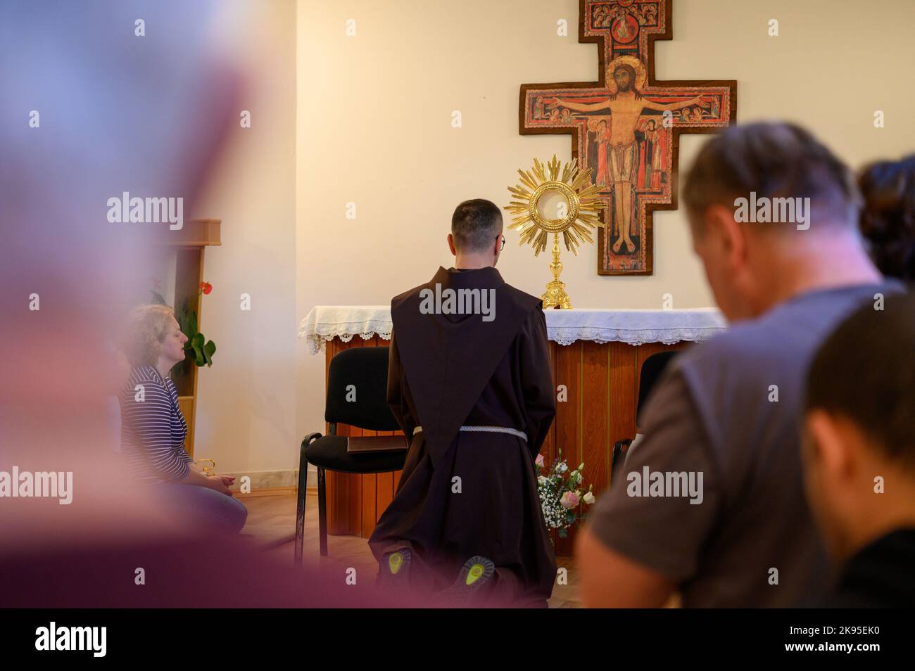 A Franciscan friar with the faithful adoring Jesus in the Most Blessed Sacrament during 'Prayer, fasting and silence seminar' in Medjugorje. Stock Photo