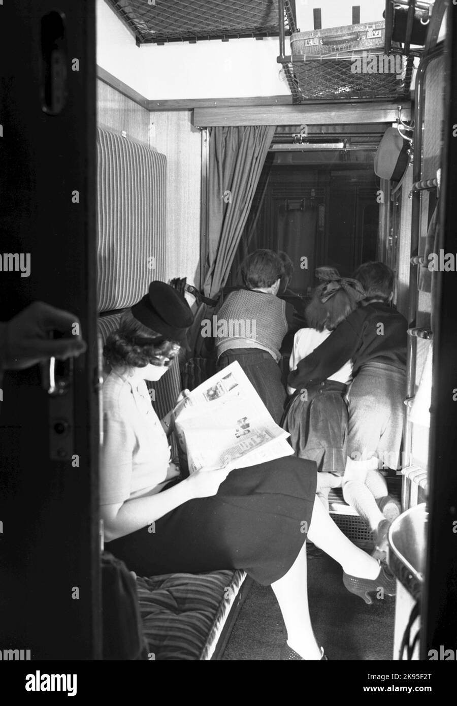 AB02C, 3rd grade sleeping car. The woman reads the newspaper and the