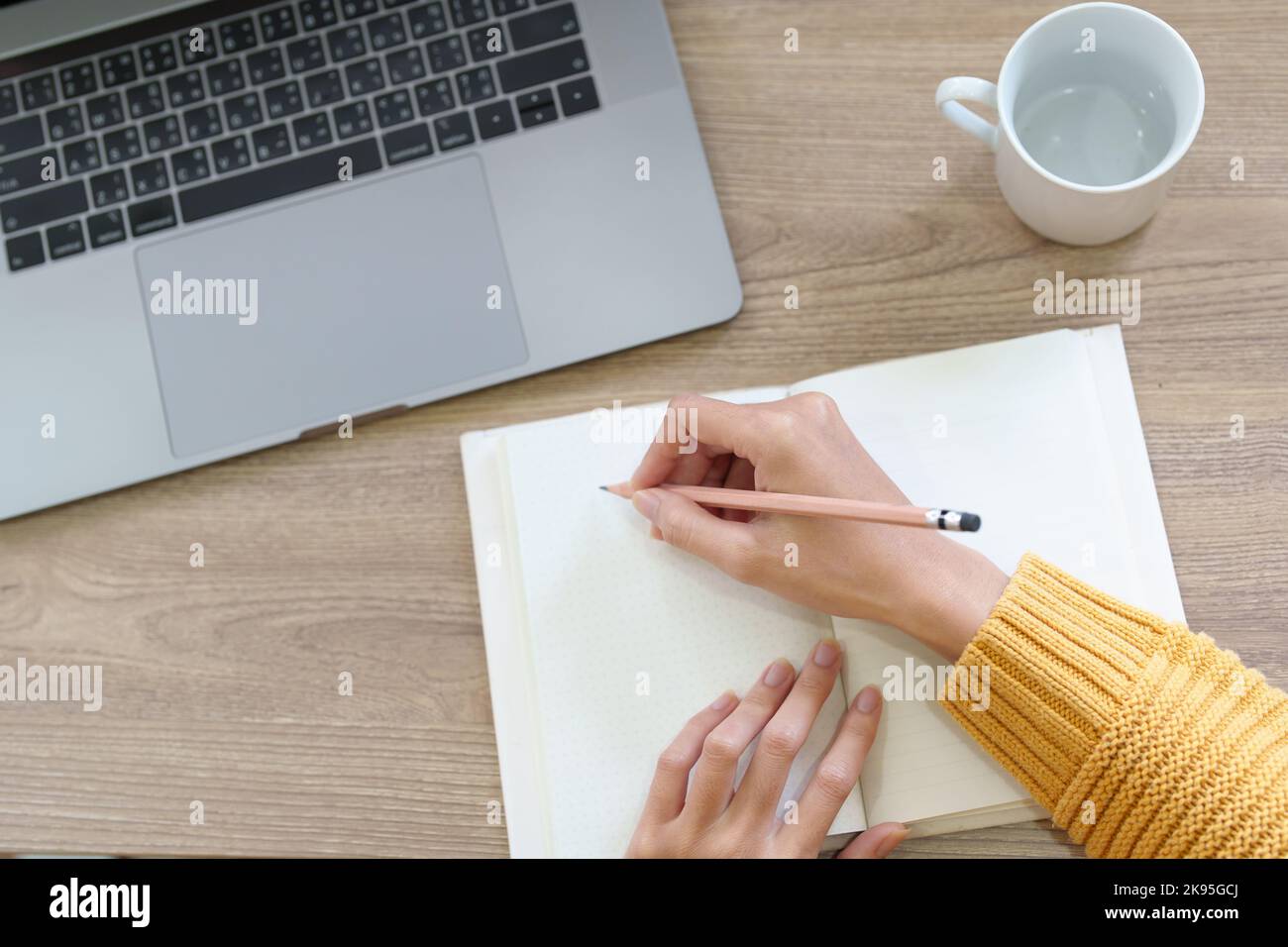 A woman using a pencil to write down memories in a notebook Stock Photo
