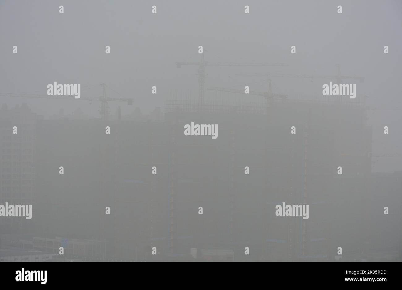 Building work with big cranes in China shrouded under a thick layer of smog Stock Photo