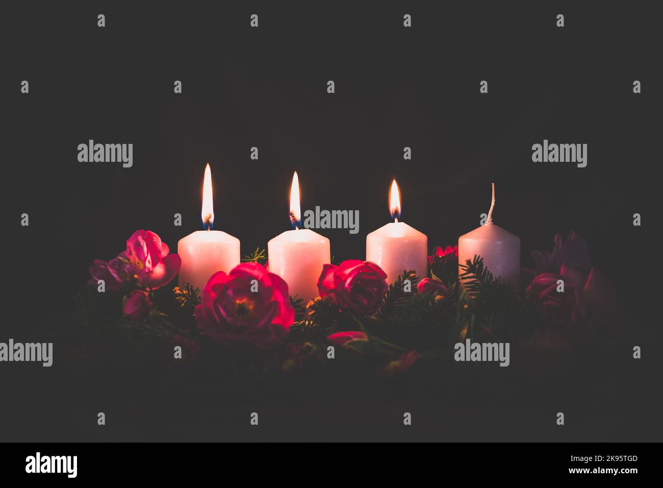 third burning advent candle on decorated rose flower pink advent wreath