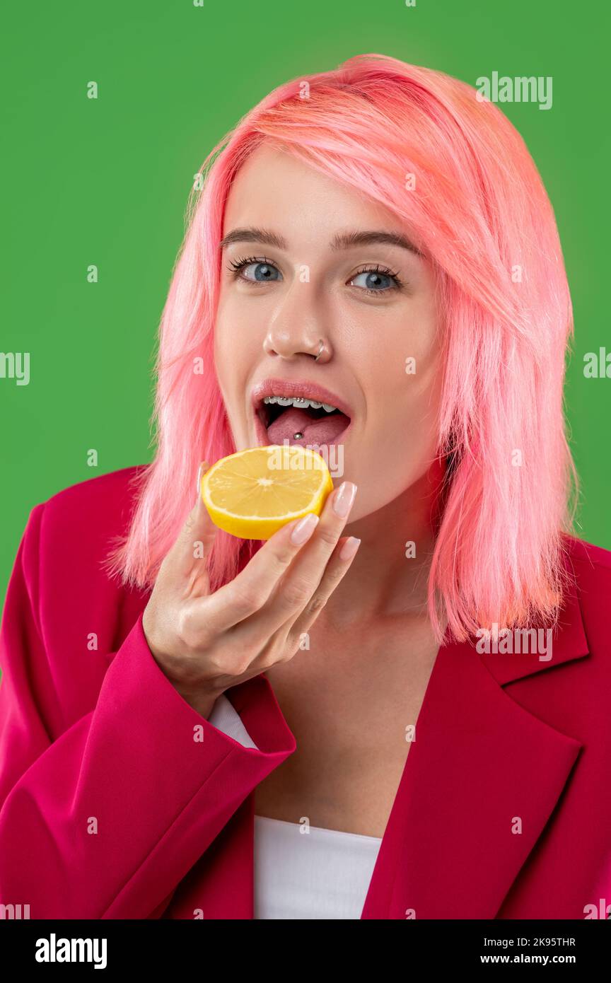 Young female eating the sliced citrus fruit before the camera Stock Photo