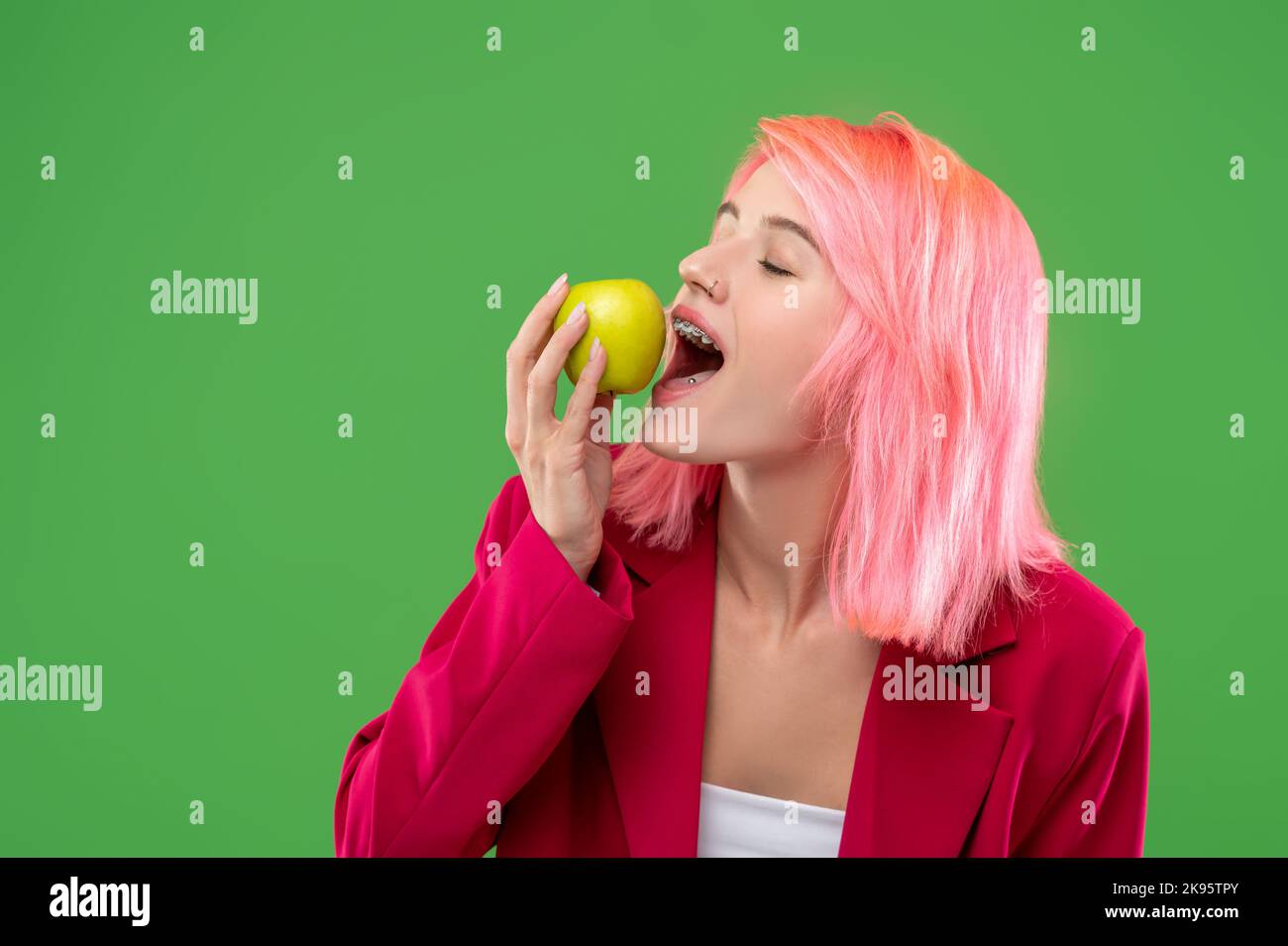Stylish young lady eating fruit in front of the camera Stock Photo