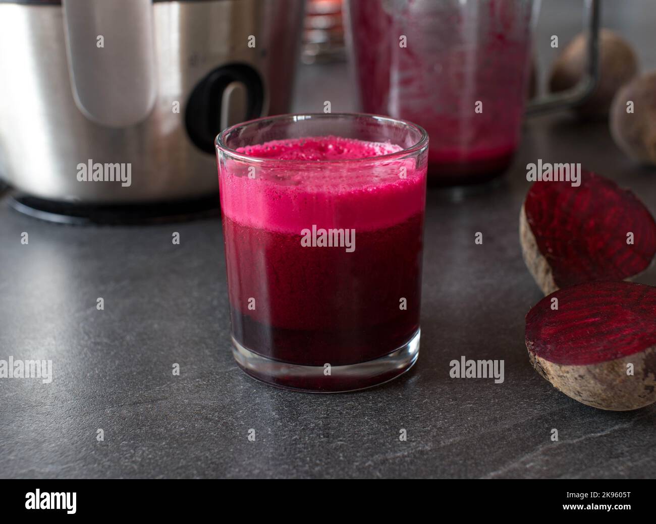 Beetroot juice freshly squeezed in a drinking glass on kitchen table Stock Photo