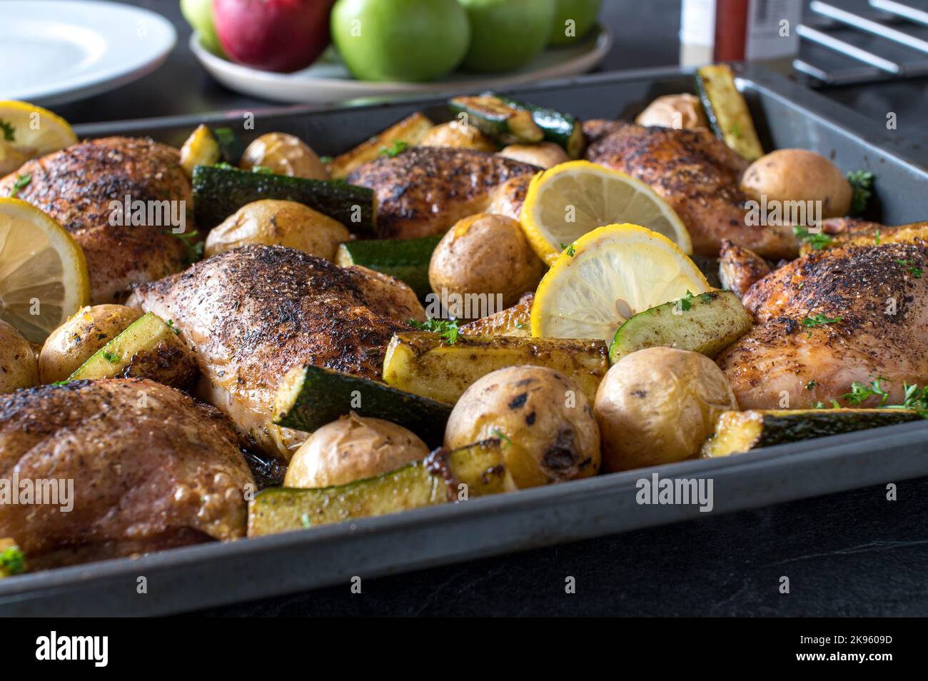 Oven baked chicken legs with potatoes and zucchini on a baking sheet