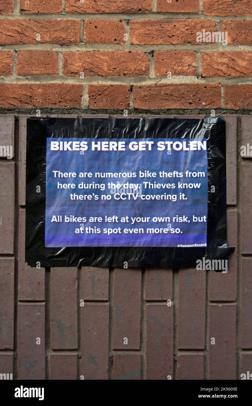 above a cycle parking rack, a sign warns cyclists that the area is not covered by cctv and cycle thefts are known here, in kingston, surrey, england Stock Photo