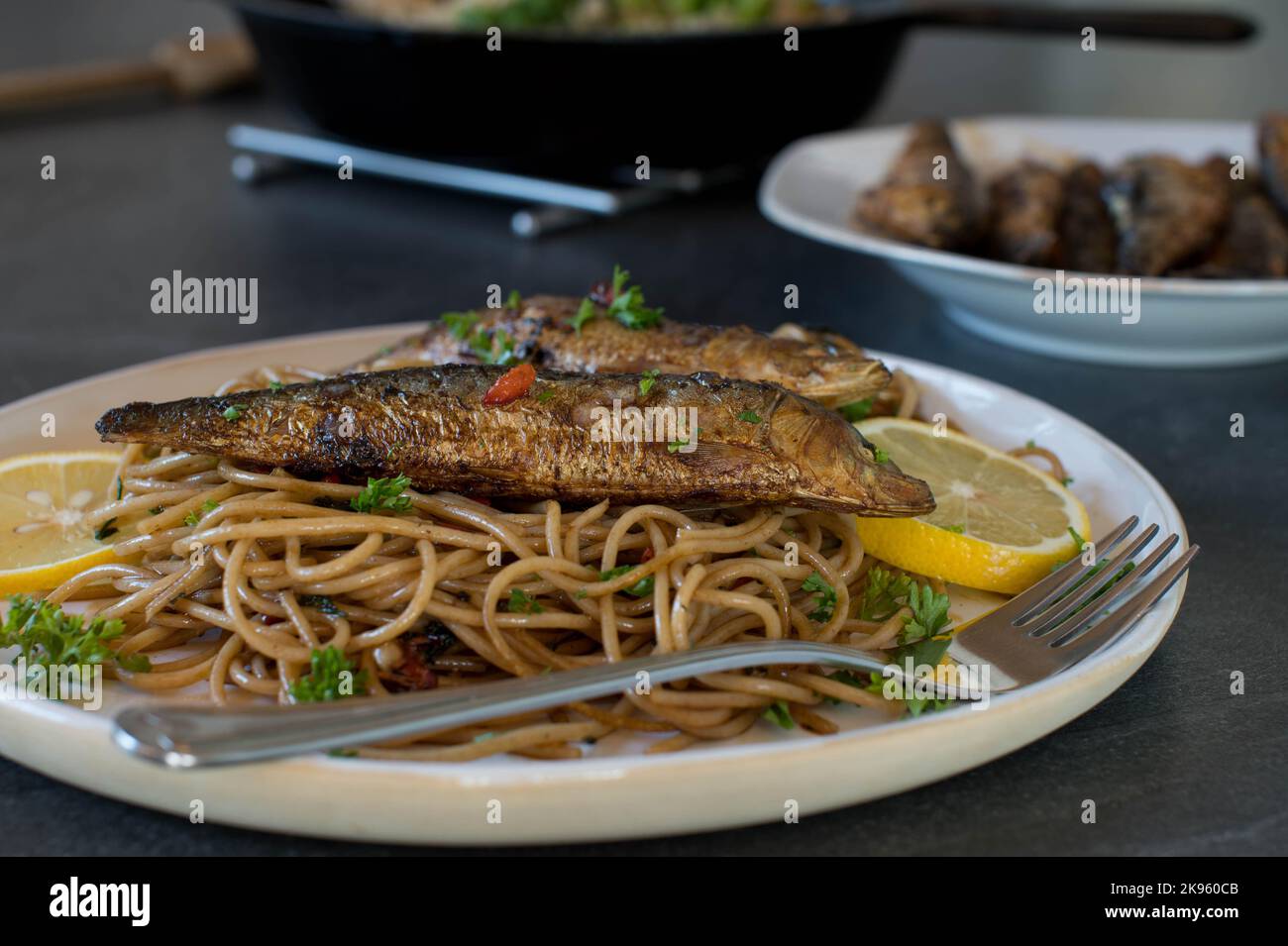 Homemade Spaghetti aglio e olio with fried sardines on a plate. Cooked