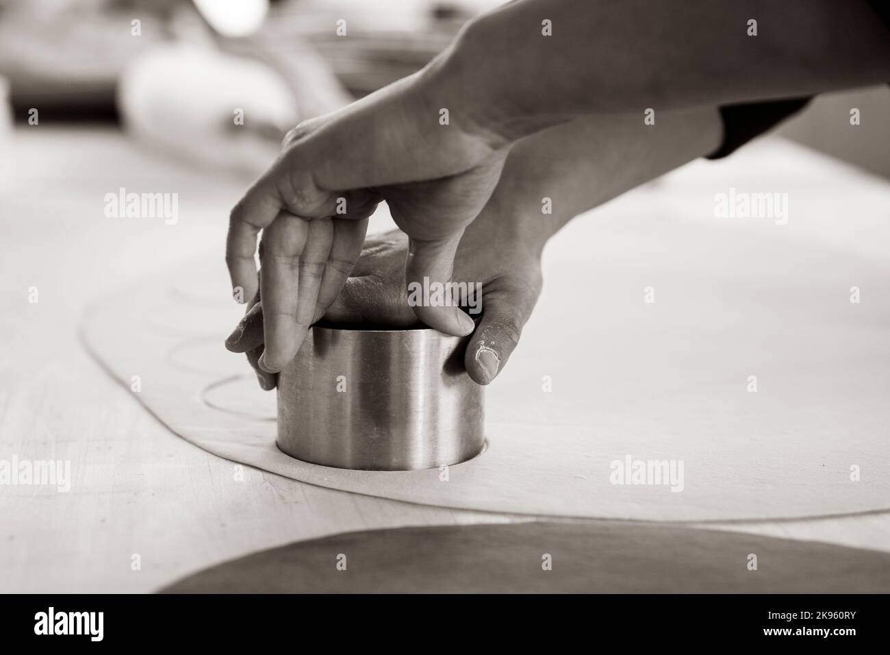 Woman working inside pasta factory or restaurant and stamping fresh made ravioli, culurgiones, agnolotti. Homemade fresh pasta concept Stock Photo