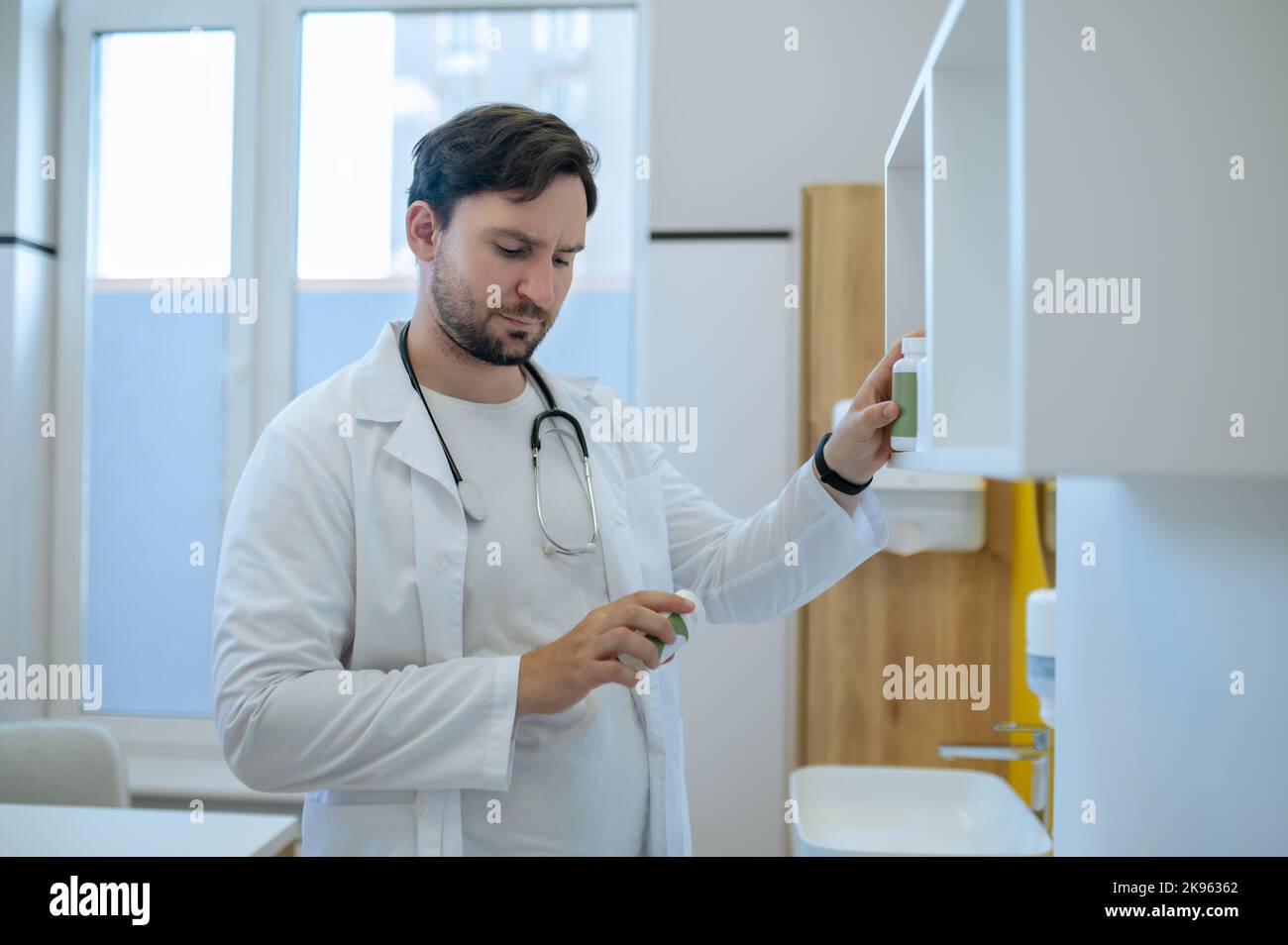 Concentrated physician checking the expiry dates of the dietary supplements Stock Photo