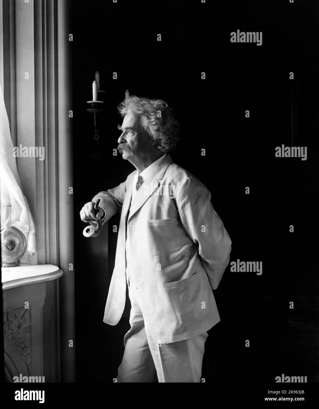 Mark Twaiin ( 1835-1910) Samuel Langhorne Clemens), three-quarter length portrait, standing by window, facing left Stock Photo