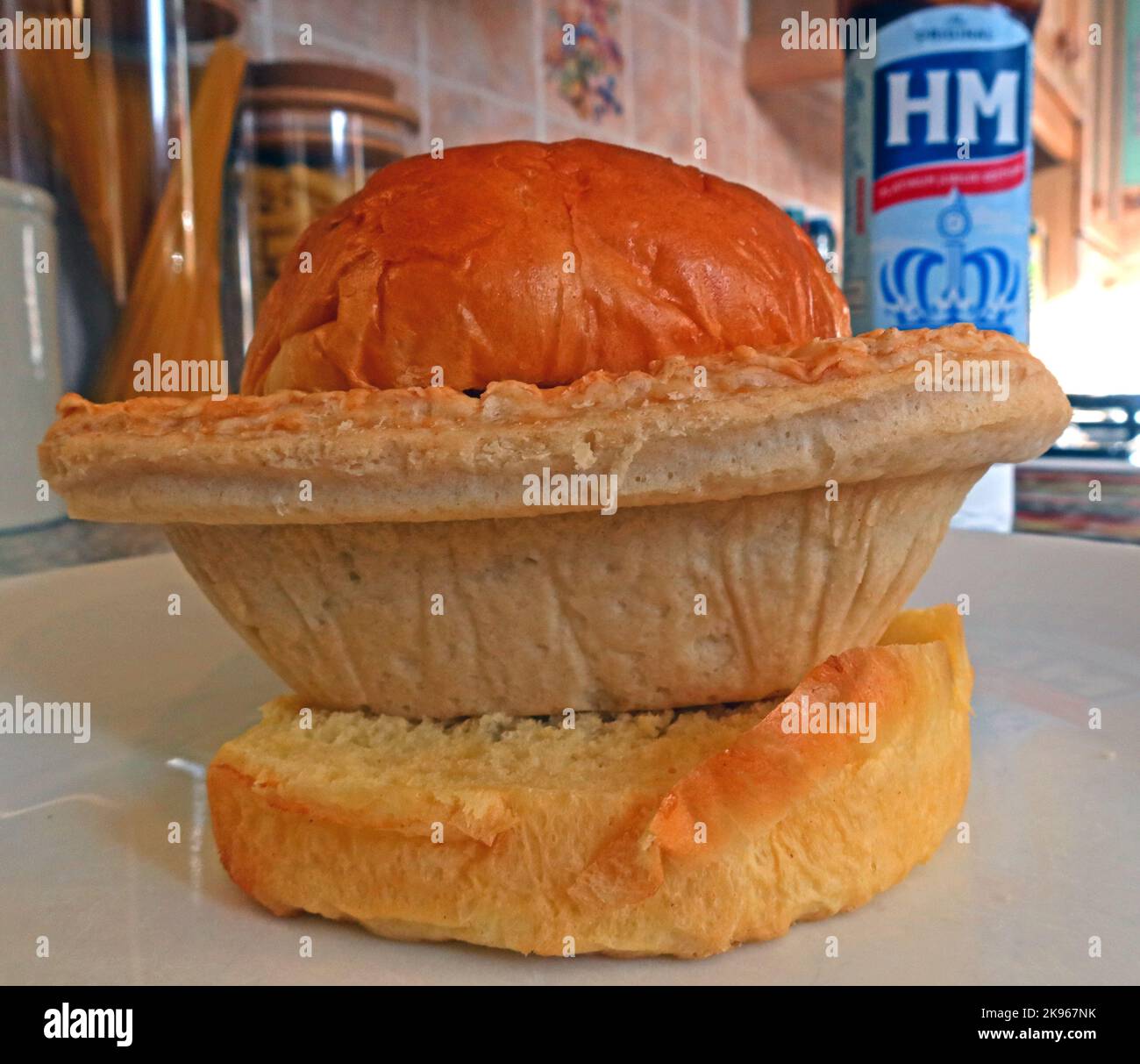 Wigan Lancashire Pie Burger, a steak or Meat pie on a oven bottom muffin, with HP Sauce bottle Stock Photo