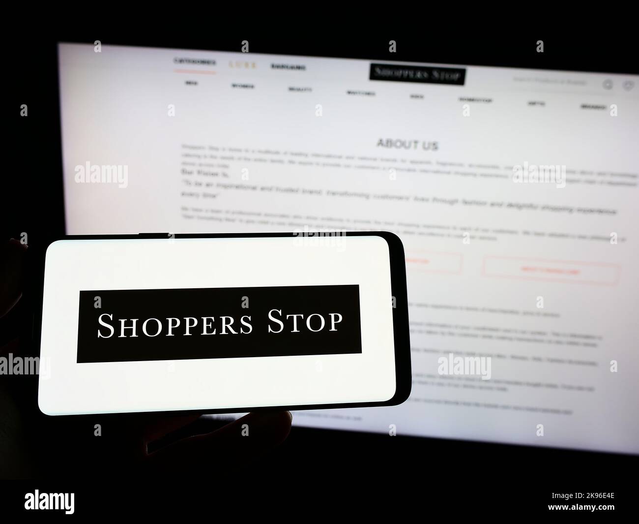 Person holding mobile phone with logo of Indian retail company Shoppers Stop Limited on screen in front of web page. Focus on phone display. Stock Photo