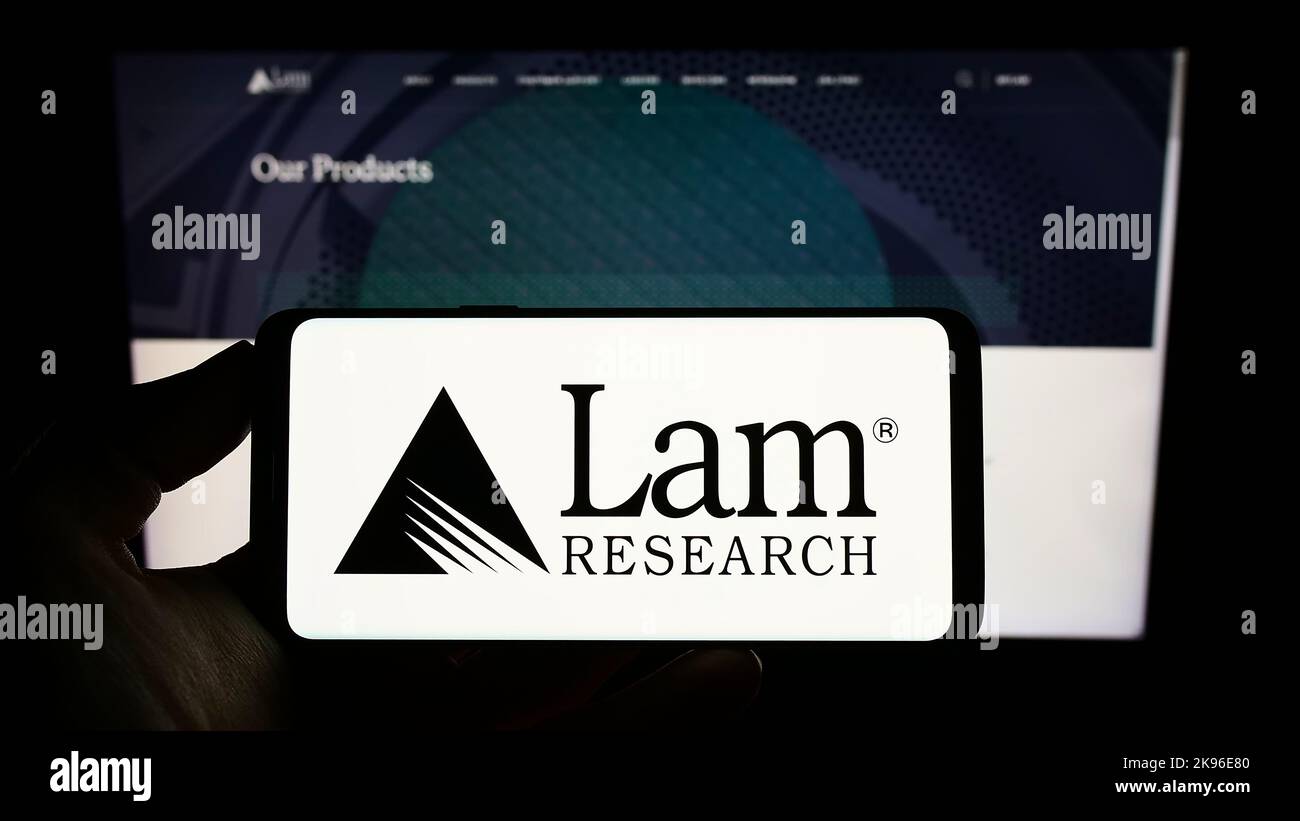 Person holding smartphone with logo of US semiconductor company Lam Research Corporation on screen in front of website. Focus on phone display. Stock Photo