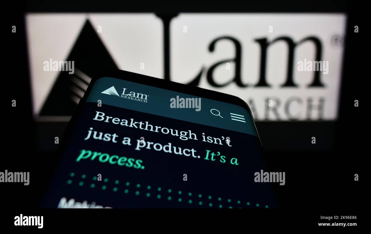 Smartphone with website of US semiconductor company Lam Research Corporation on screen in front of logo. Focus on top-left of phone display. Stock Photo