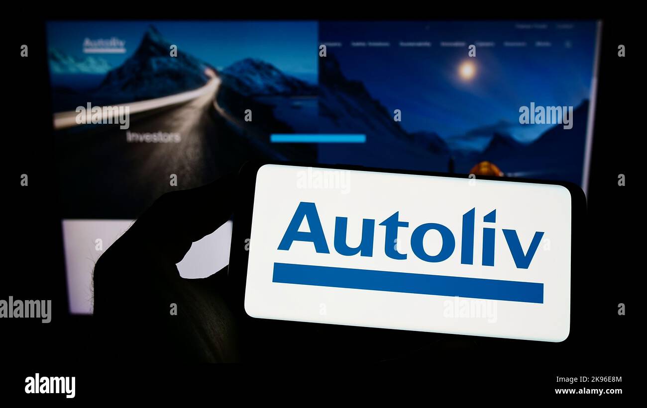 Person holding mobile phone with logo of automotive supply company