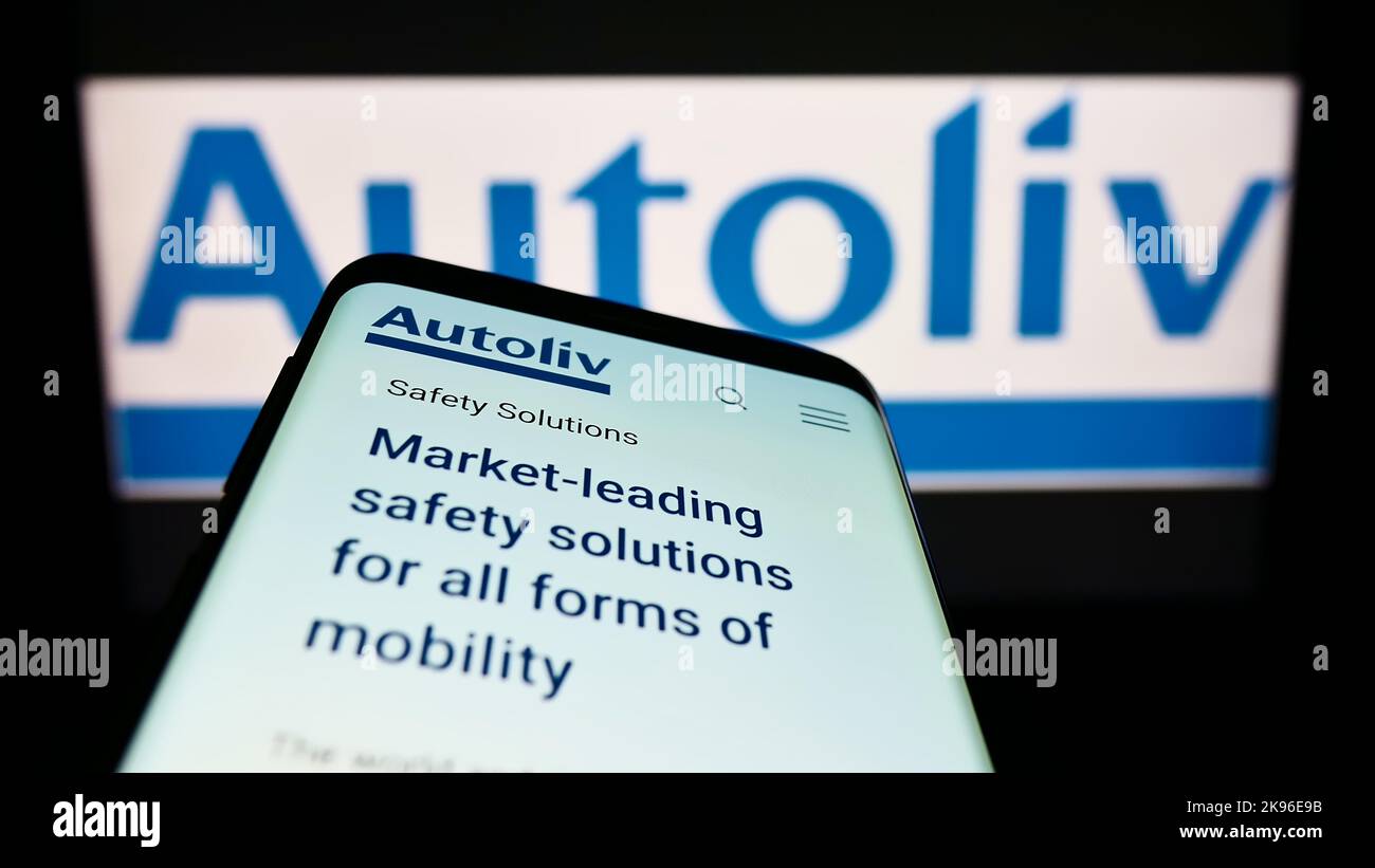 Mobile phone with website of automotive supply company Autoliv Inc. on screen in front of business logo. Focus on top-left of phone display. Stock Photo
