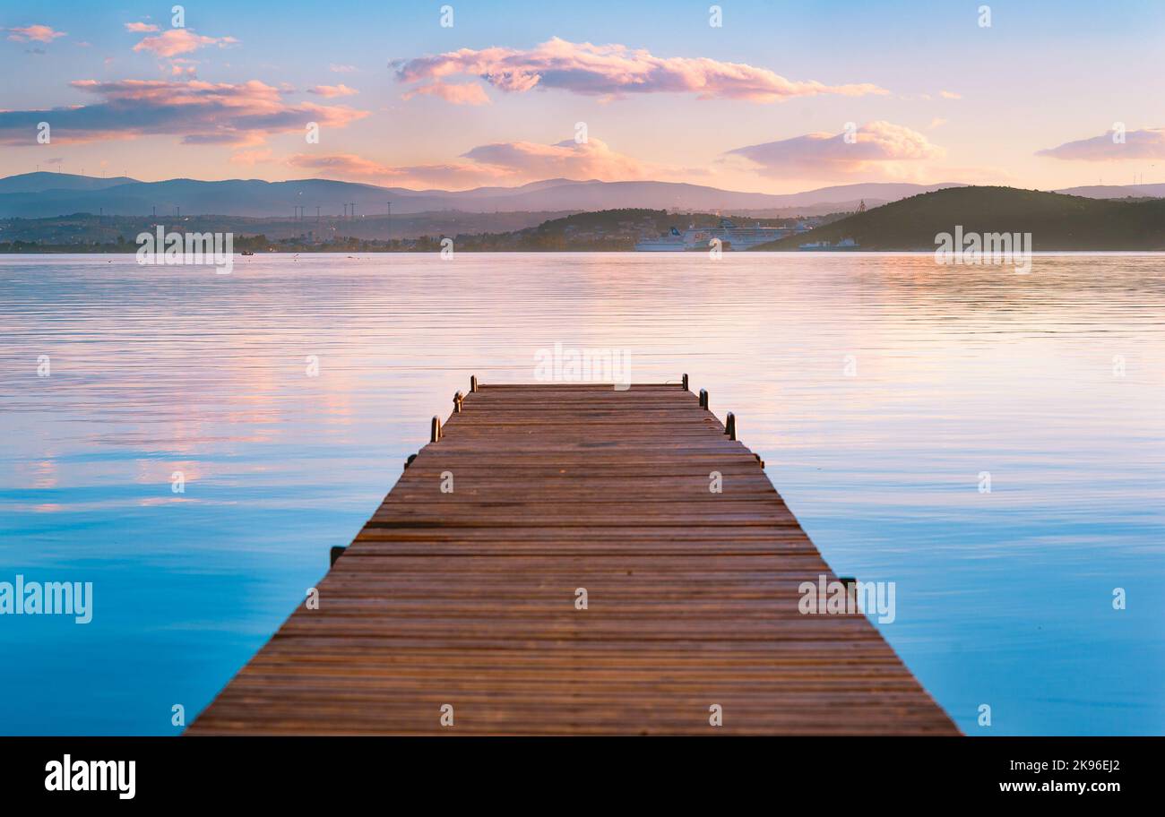 A long wooden dock over a lake at sunset in Evoia, Greece Stock Photo
