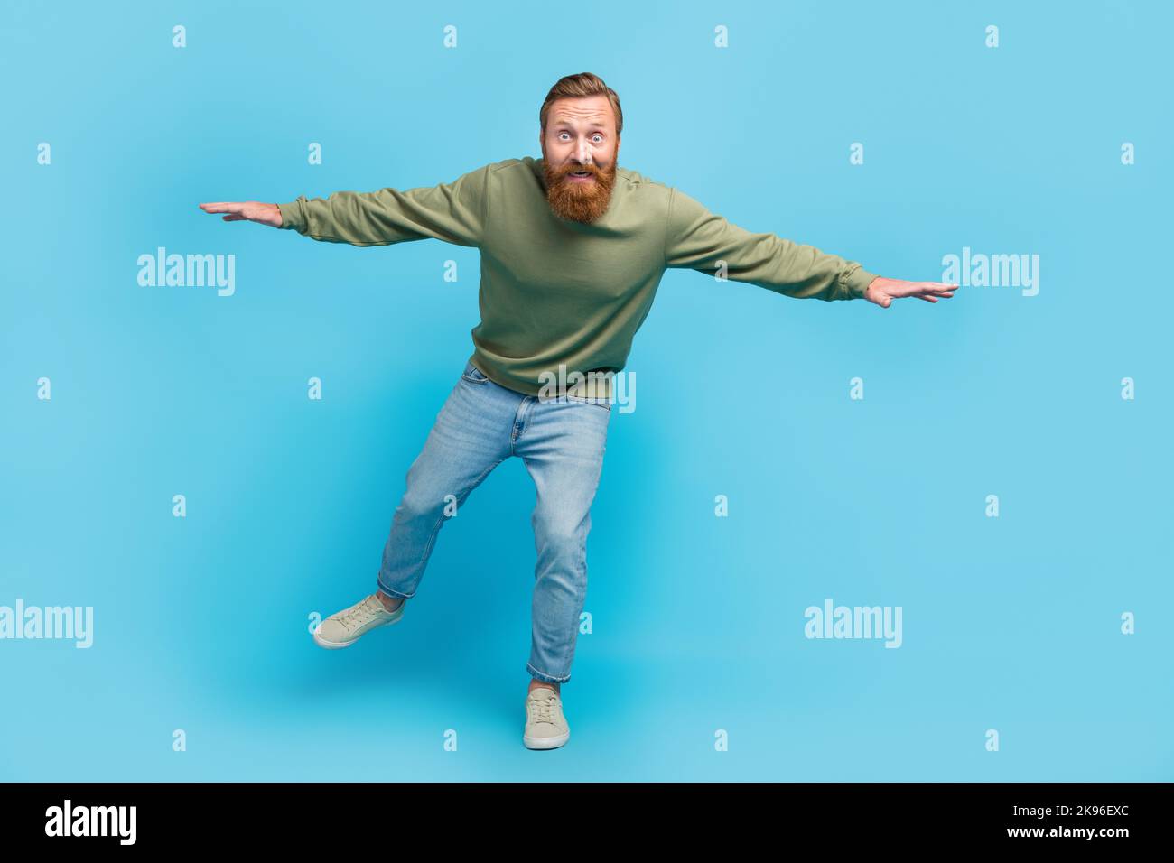 Full body photo of attractive young man frightened try not fall down dressed stylish khaki clothes isolated on aquamarine color background Stock Photo