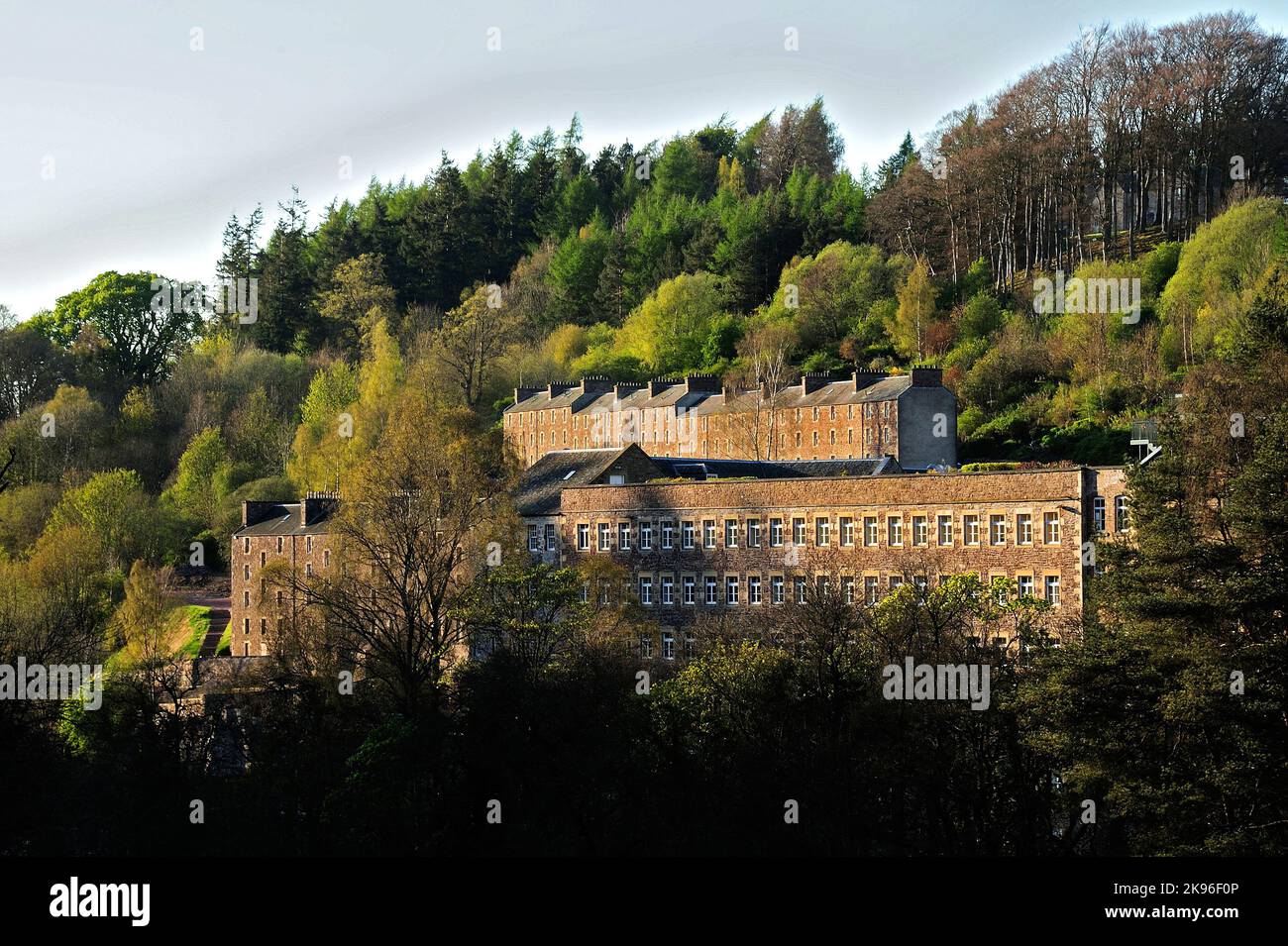 An outdoor view of the New Lanark Mill Hotel and forest in Scotland
