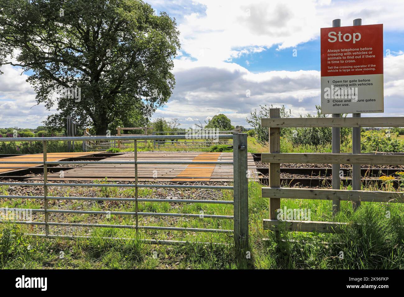 A warning sign on an unmanned railway level crossing with manualy operated gates, Nantwich, Cheshire, England, UK Stock Photo