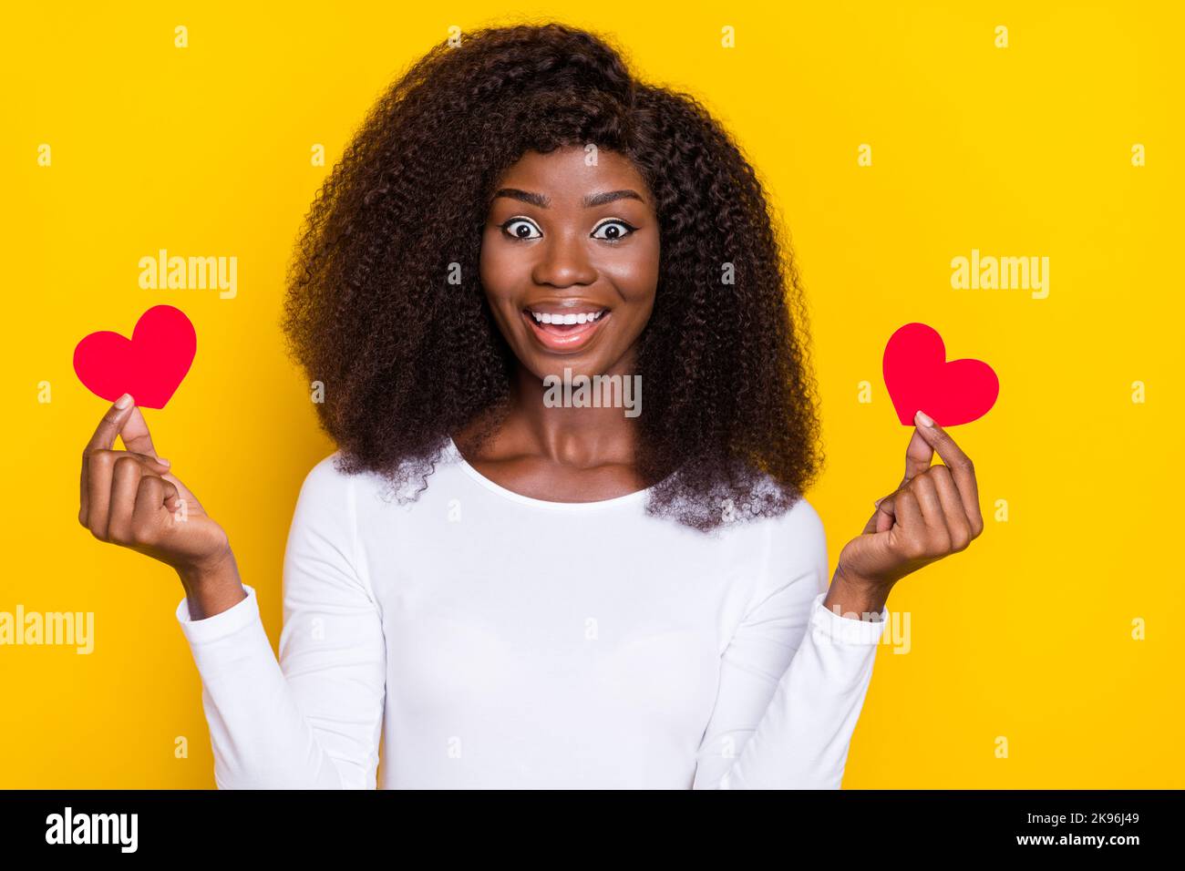 Portrait of positive adorable girl hold two little paper red heart ...