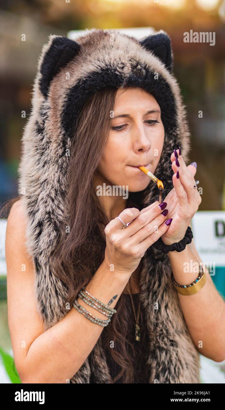 A young woman in a Halloween hat smokes a hemp flower (Cannabis sativa) joint, which is legal in NC, USA Stock Photo