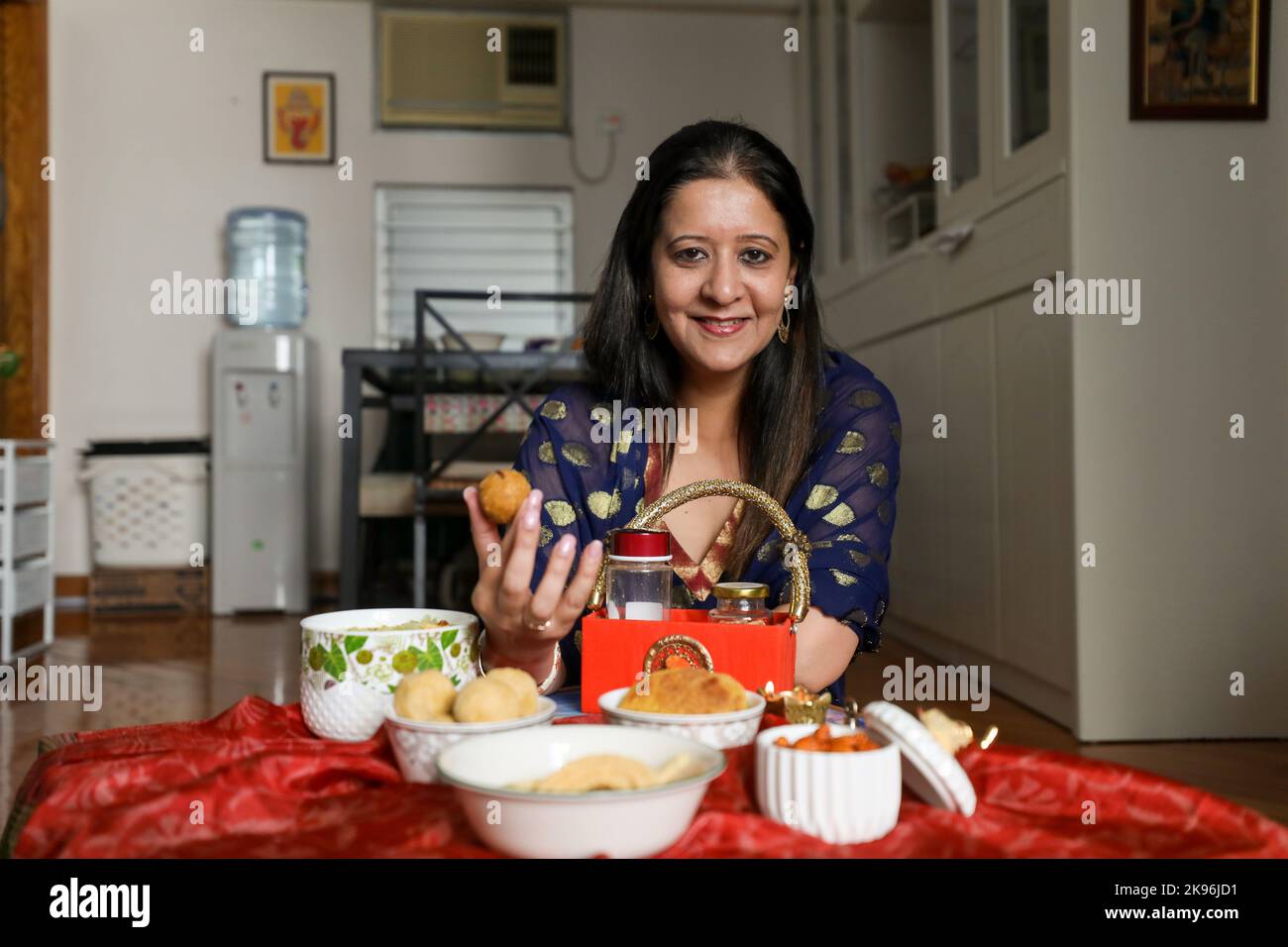 Reema Shankar photographed at home in Lam Tin with Indian snacks she prepared for Diwali. Snacks: front from left, Chevda , Besan Laddoo, chakri; back from left, masala cashews, bhakri. 08OCT22 SCMP / Xiaomei Chen Stock Photo