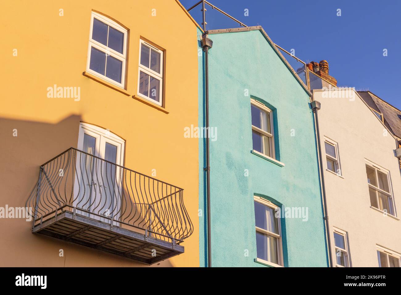 Exterior of semi detached houses with coloured rendered walls with blue sky.  UK Stock Photo