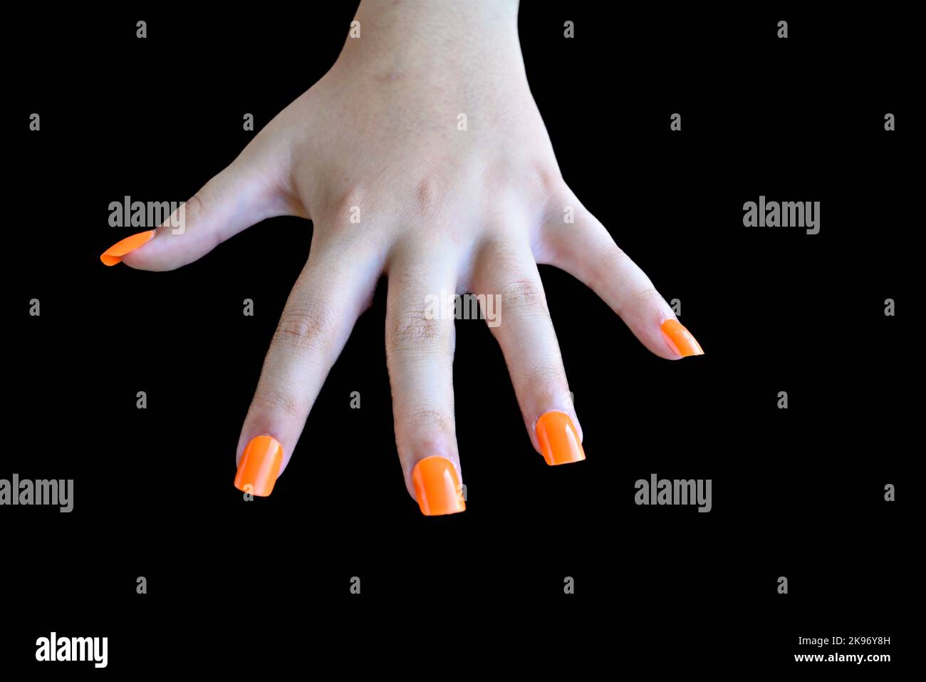 Girl's hands with orange false nails on a black background. female manicure Stock Photo
