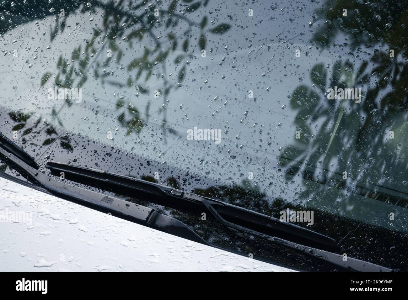 Car wipers and windshield with raindrops on it, closeup photo with selective focus Stock Photo