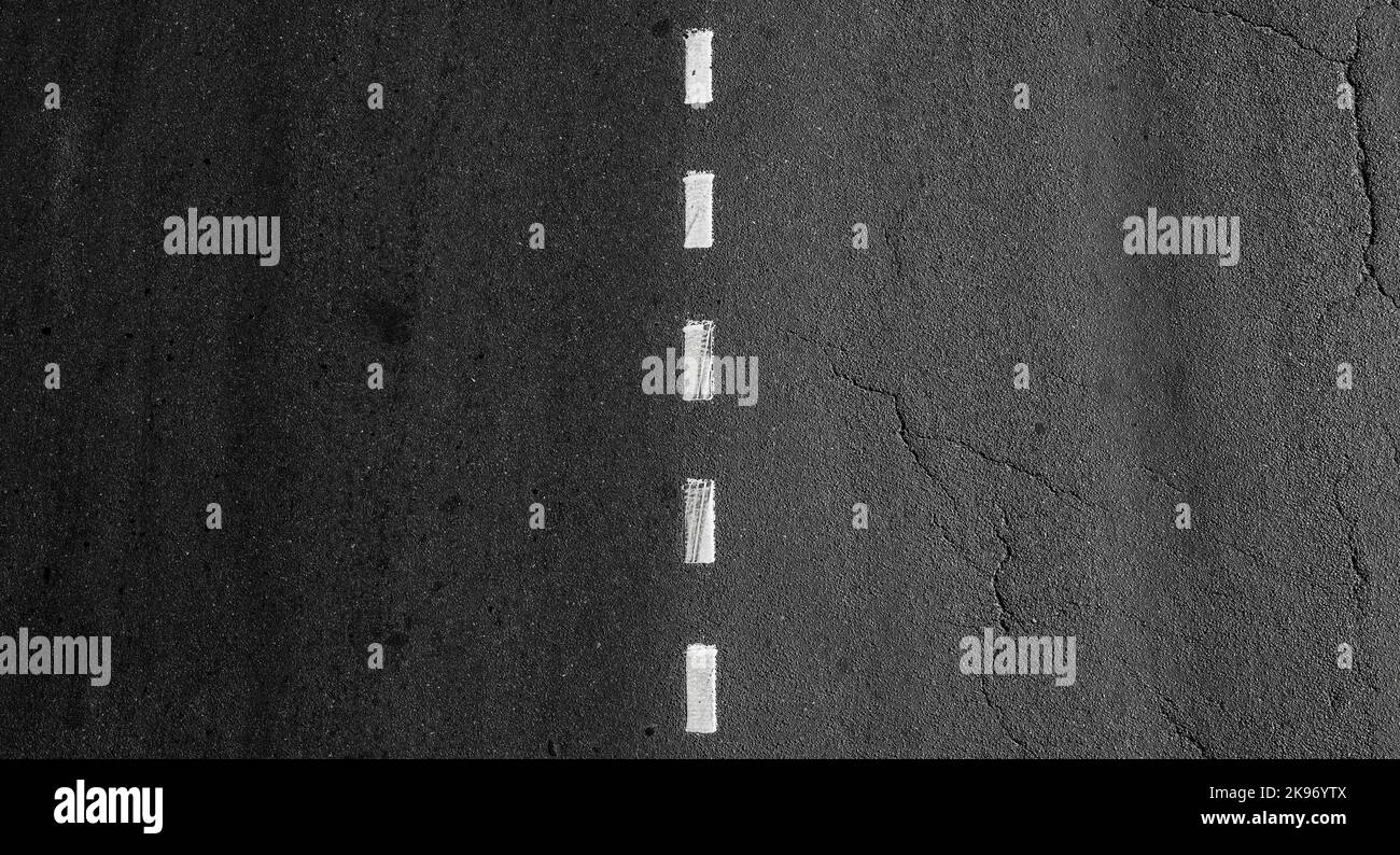 Dotted dividing road marking line goes over dark asphalt highway Stock