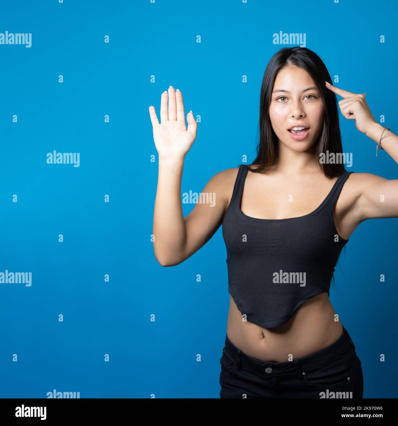 Young multiracial trendy woman with big smile holding and presenting copy space on the side of her palm isolated on blue background Stock Photo