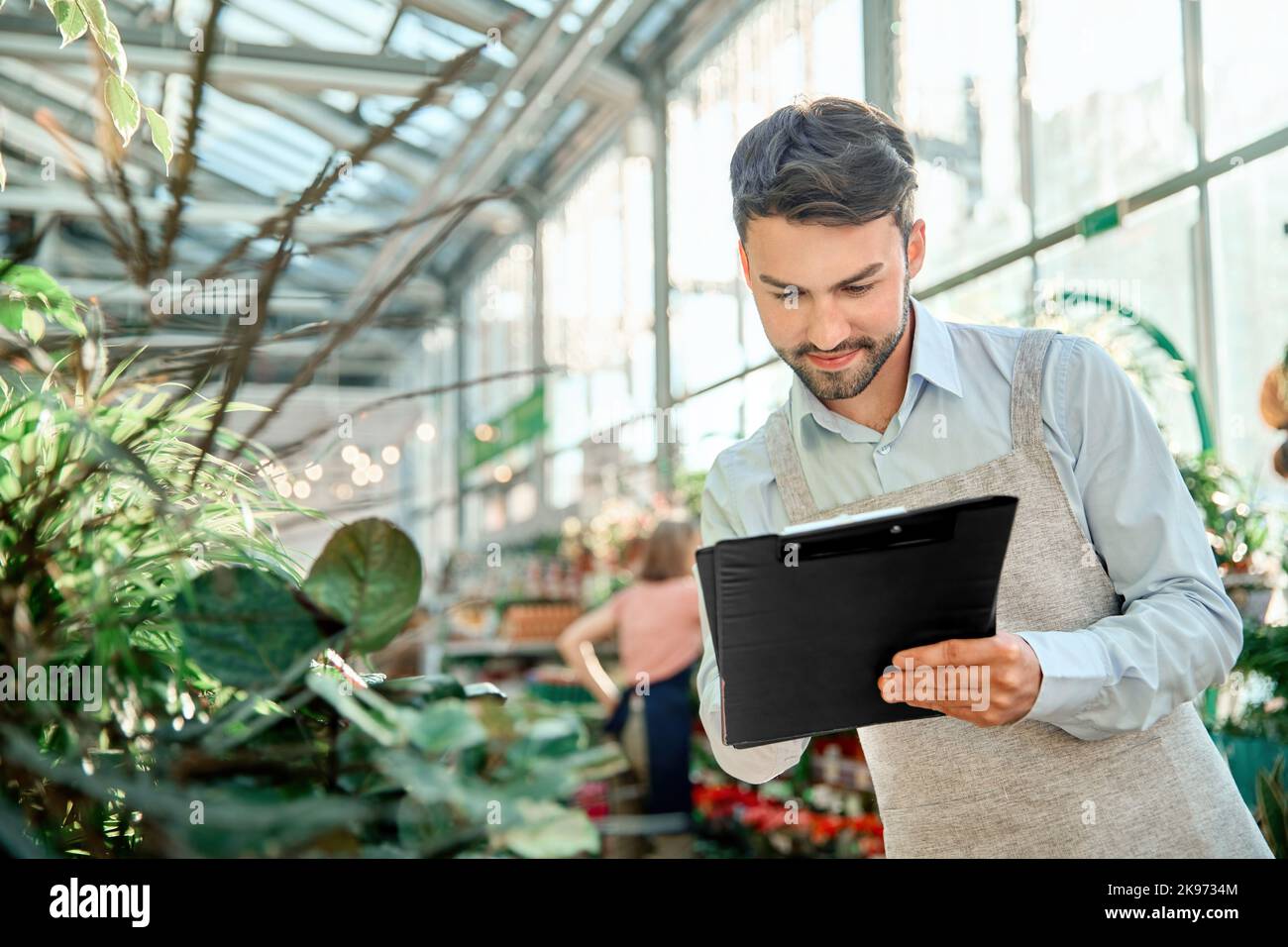 male florist taking notes on the clipboard. Stock Photo