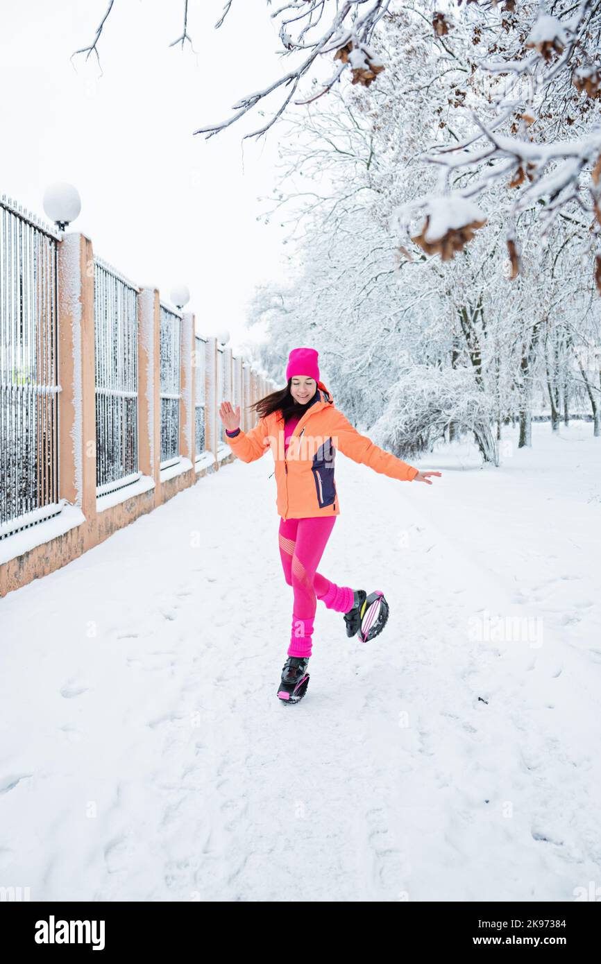 Winter workout, exercising in cold weather. Winter fitness Trening kangoo jumps. Sporty woman in sportswear and kangoo jump shoes jumping in winter Stock Photo