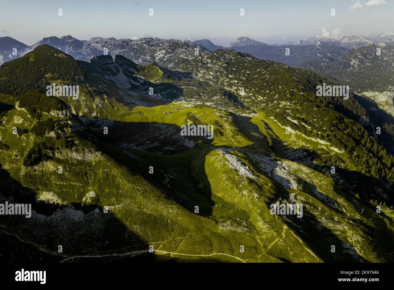 An aerial shot of high green mountains reflecting the sunlight on a ...