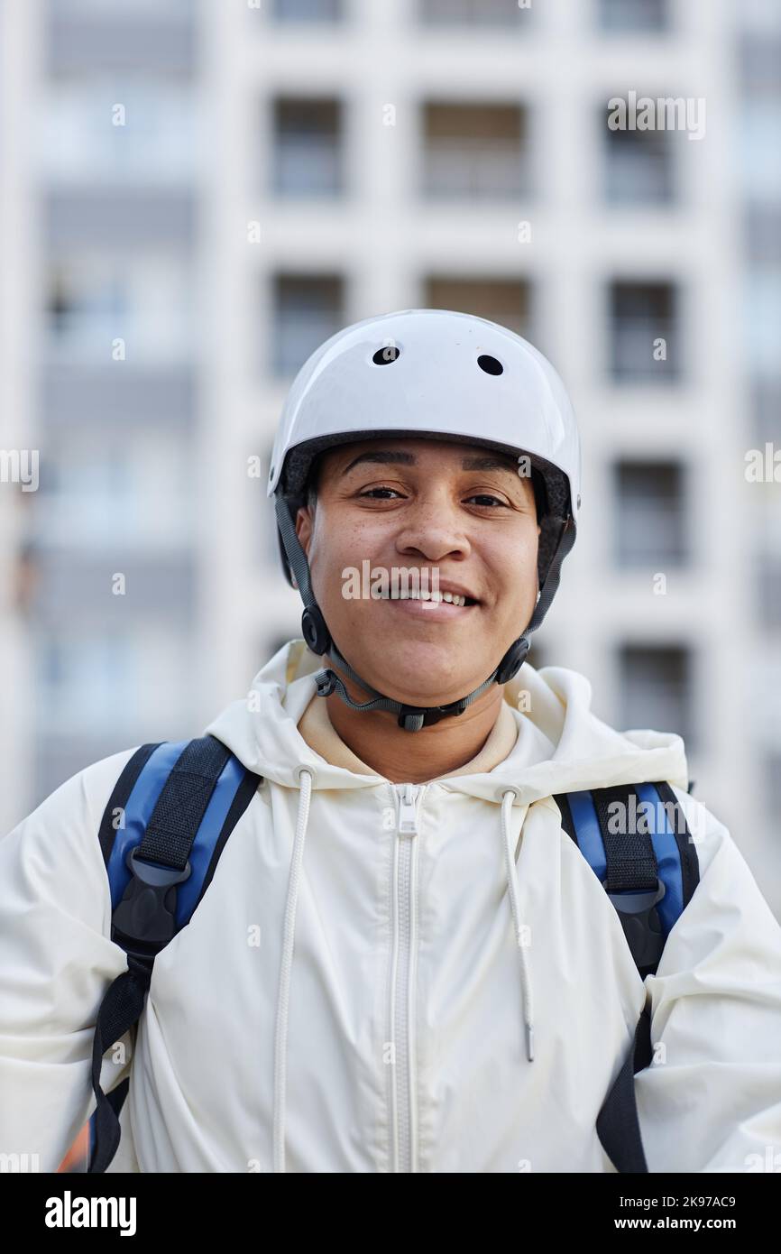 Vertical portrait of smiling food delivery worker wearing helmet while