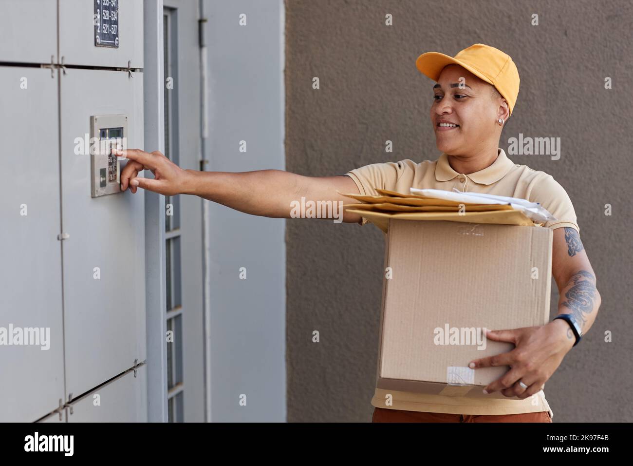 Side view portrait of female delivery worker ringing doorbell and holding box Stock Photo