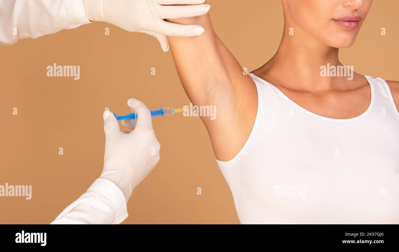 Hyperhidrosis treatment. Young lady receiving underarm shot to prevent excessive sweating, cropped, closeup Stock Photo