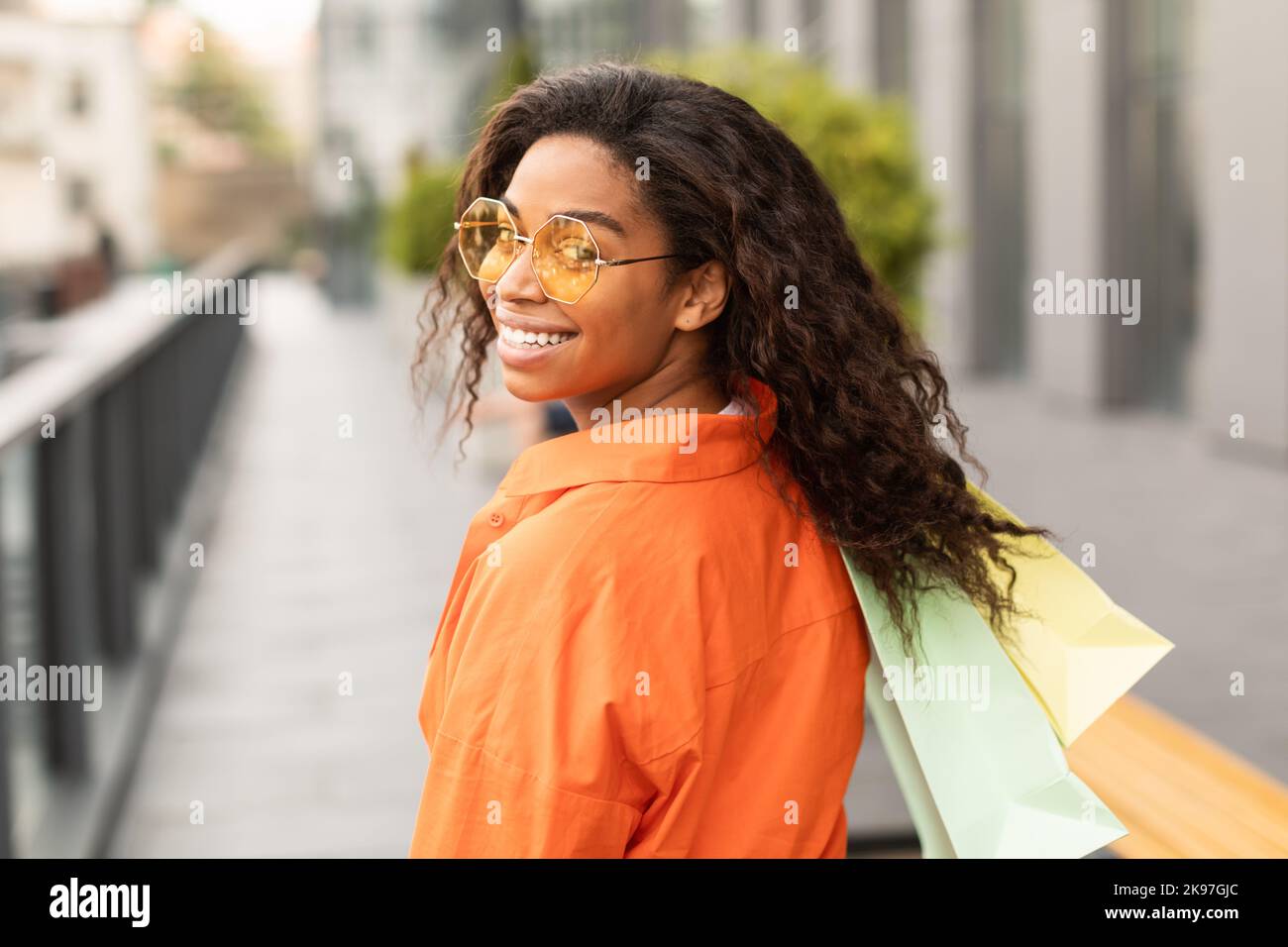 Fashion lifestyle. Happy millennial african american lady customer in casual and glasses with many bags Stock Photo