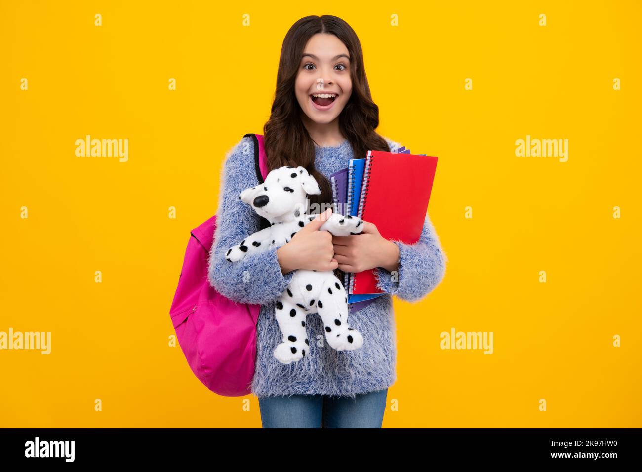 Schoolgirl 12, 13, 14 years old with toy. School children cuddling favorite toys on yellow background. Happy childhood. Happy teenager, positive and Stock Photo
