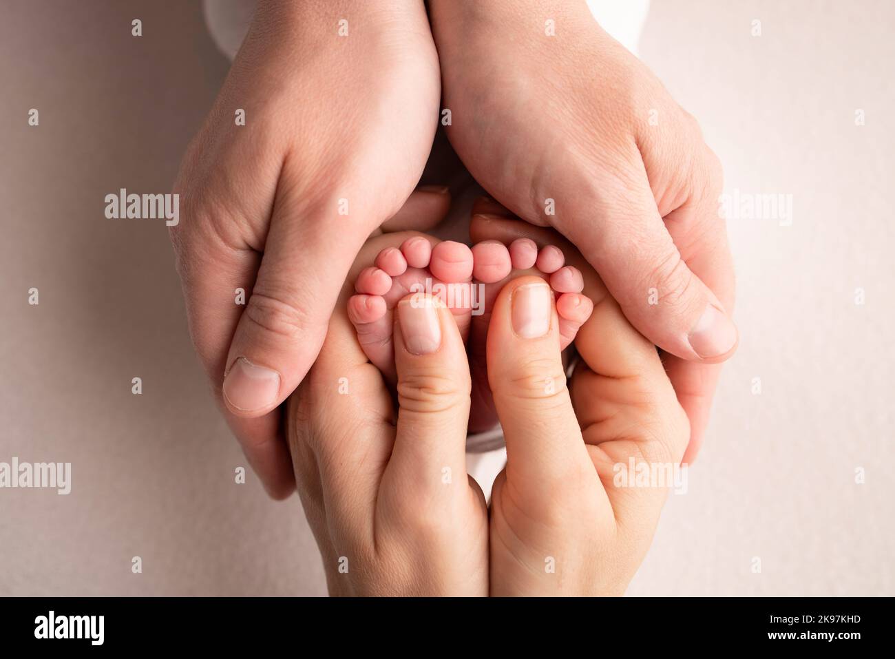 Mother and father are doing massage on her baby foot. Closeup baby feet in mother hands.  Stock Photo