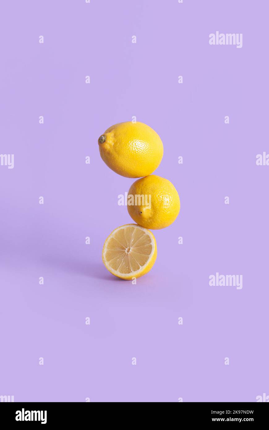 Composition of lemons on a pastel purple background in balance Stock