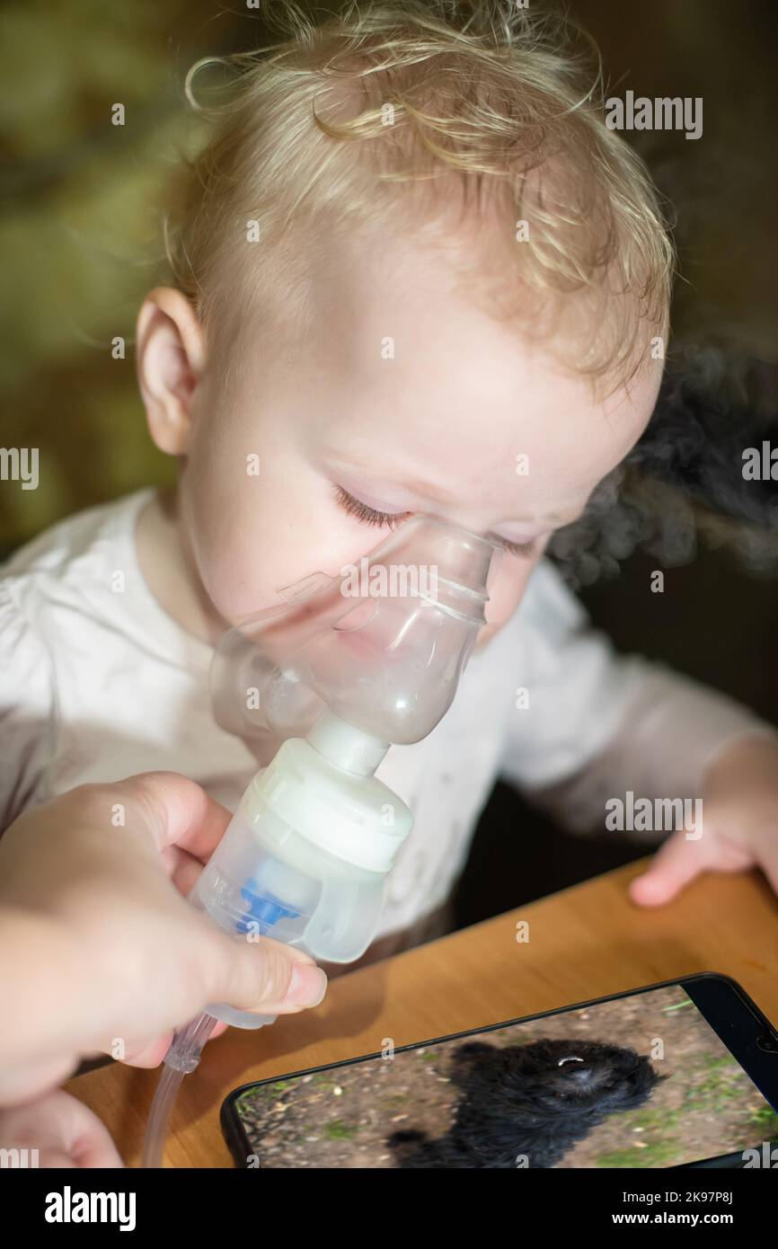 Inhalation makes child at home. Treatment of disspirators diseases with nebulizer with medication. Stock Photo