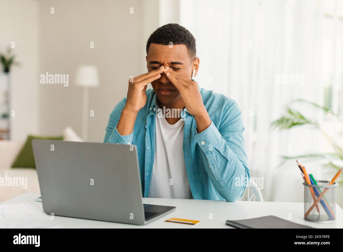 Sad tired young black male resting from work with laptop, suffering from migraine Stock Photo