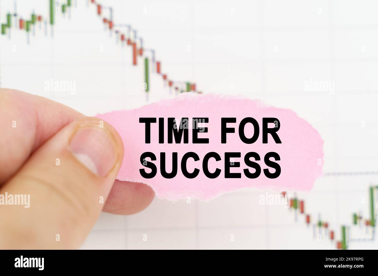 Business and trading concept. Against the background of the quote chart, a man holds a sign with the inscription - TIME FOR SUCCESS Stock Photo