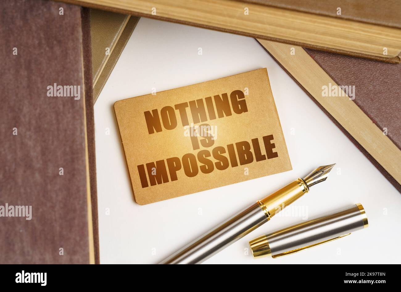 Education and business concept. Next to the books lies a pen and a sign with the inscription - Nothing is Impossible Stock Photo