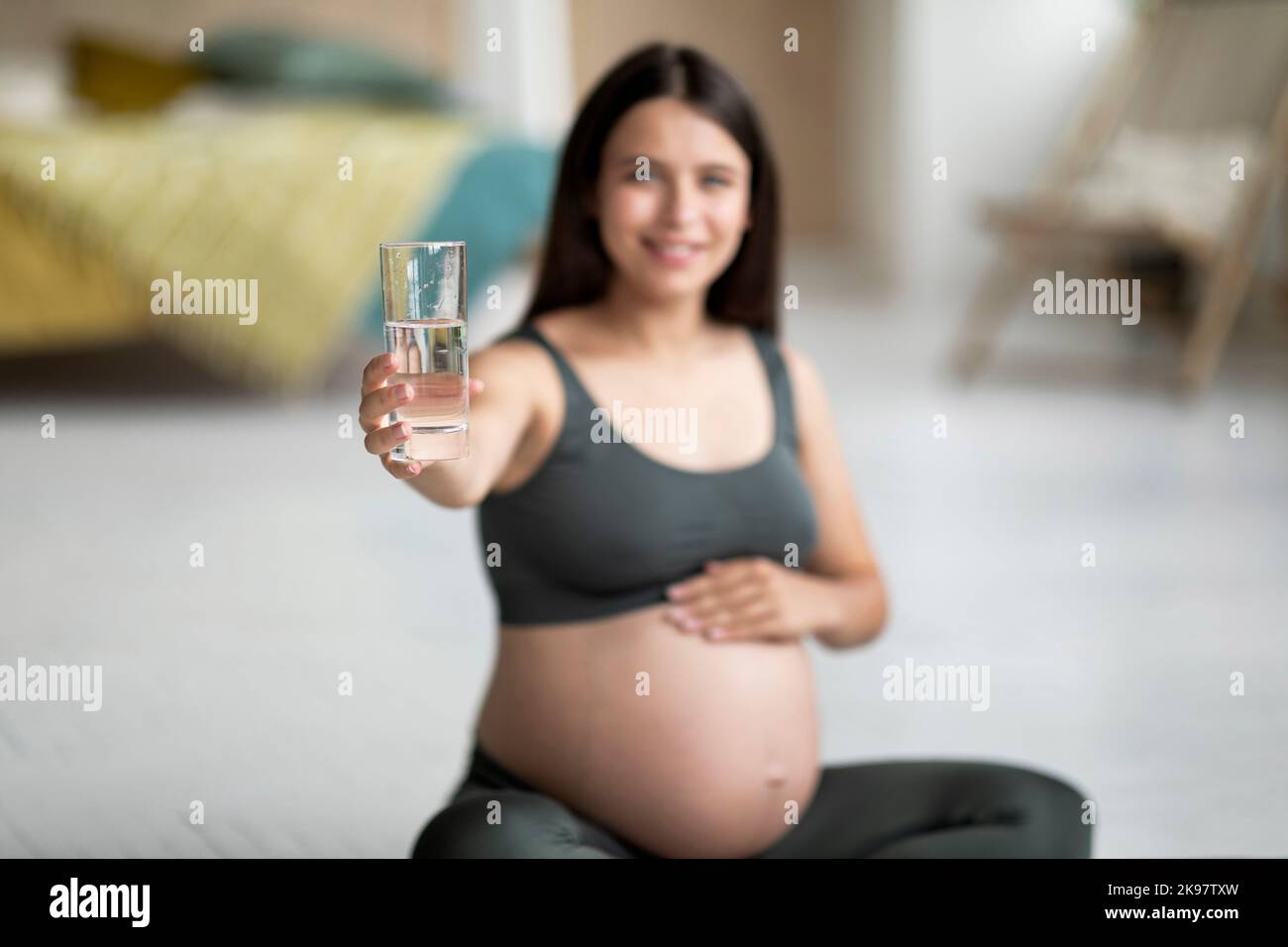 Healthy Drink. Smiling Pregnant Lady Giving Glass With Water At Camera Stock Photo